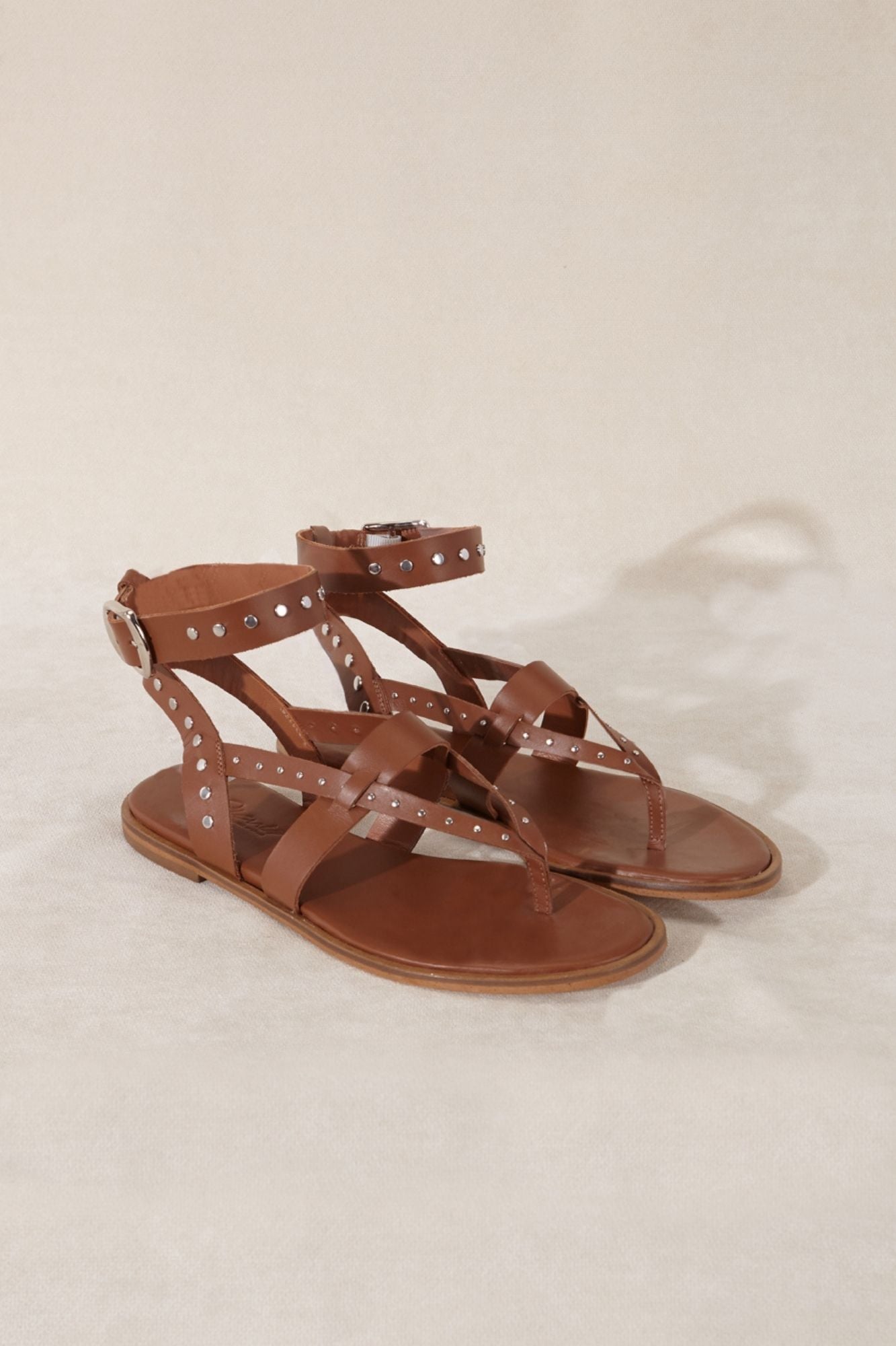 Sandalia de piel color marrón con detalles metálicos y correas tobilleras hecho en España